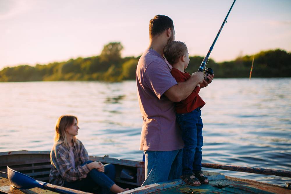 A man and two children fishing on a boat.